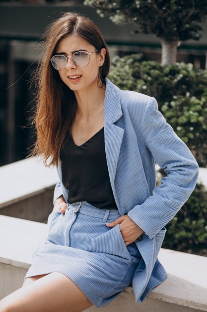 Mujer joven sentada en las escaleras con un traje azul