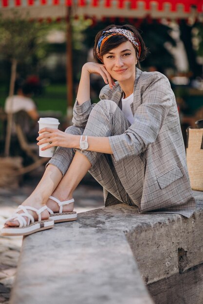 Mujer joven sentada junto a la fuente y tomando café