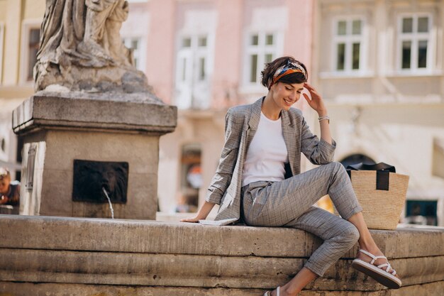 Mujer joven sentada junto a la fuente