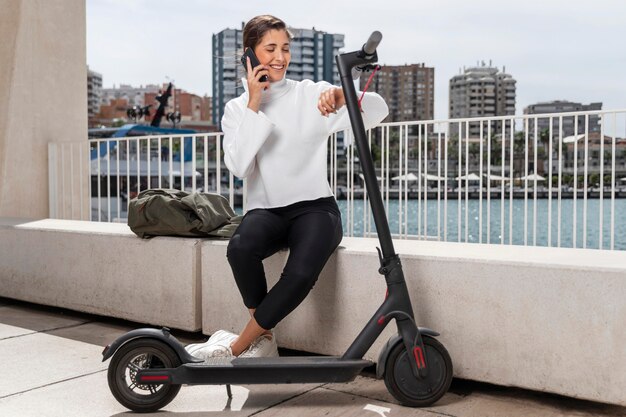 Mujer joven sentada junto a un scooter