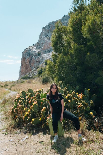 Mujer joven sentada en una maleta de equipaje durante el viaje al aire libre