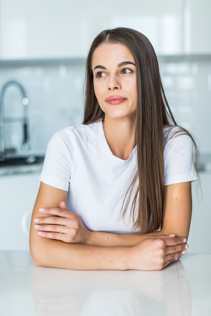 Mujer joven sentada en una mesa en la cocina.