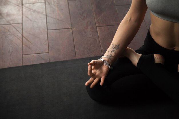 Mujer joven sentada en padmasana pose, estudio loft blanco