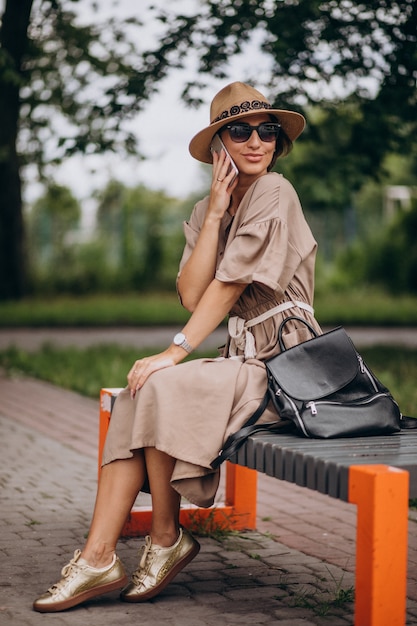 Mujer joven sentada en el parque usando el teléfono