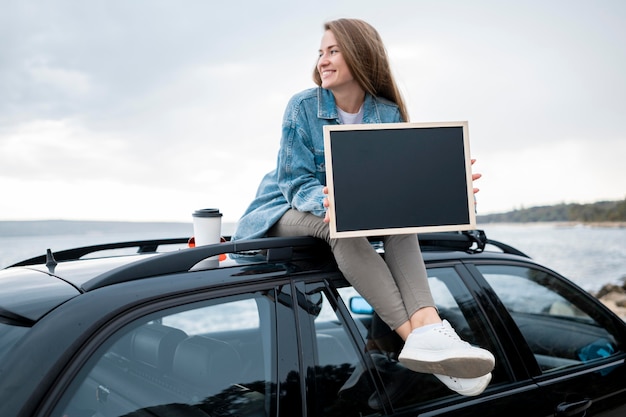 Mujer joven sentada en la parte superior del coche