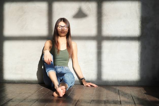 mujer joven sentada en el piso de una habitación vacía