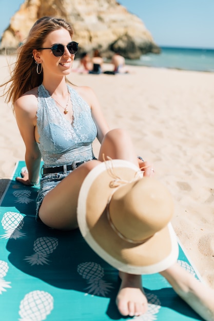 Mujer joven sentada en la playa del mar