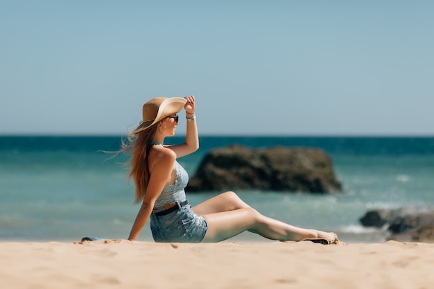 Mujer joven sentada en la playa del mar