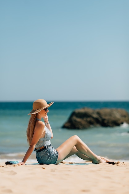 Mujer joven sentada en la playa del mar