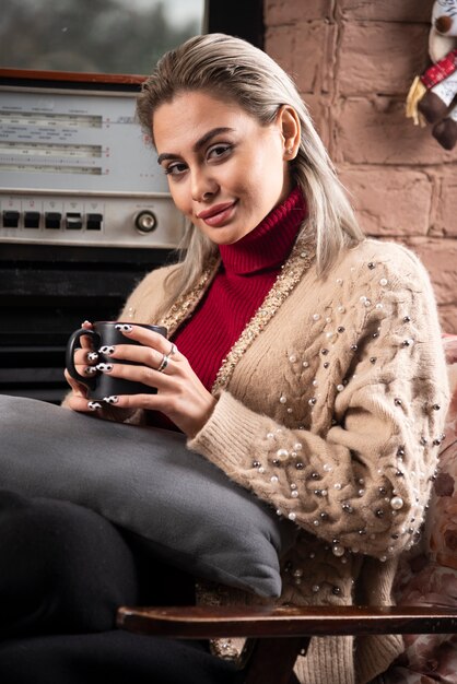 Mujer joven sentada y sosteniendo un té caliente