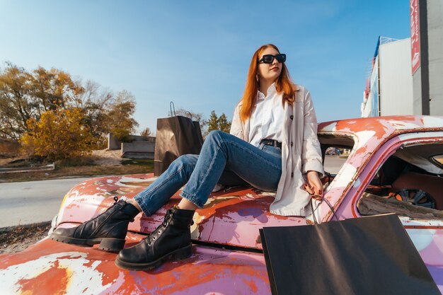 Mujer joven sentada en un viejo coche decorado