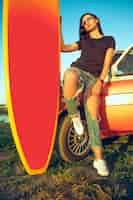 Foto gratuita mujer joven, sentado, en, coche, con, tabla de surf