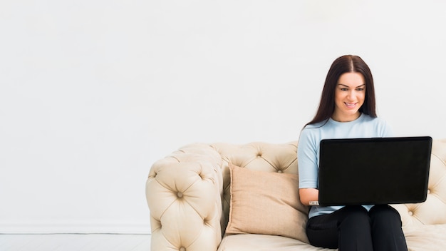 Mujer joven, sentado, con, computador portatil, en, sofá