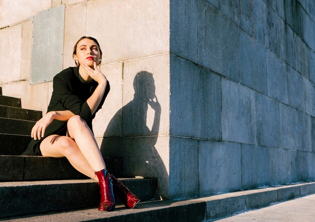 Mujer joven, sentado, en, escalera, en, luz del sol