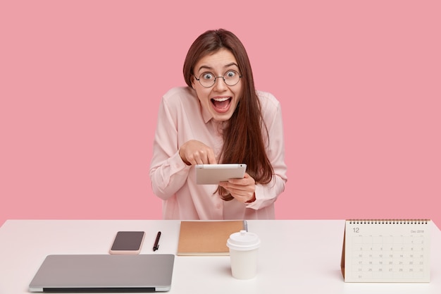 Mujer joven, sentado, en el escritorio, y, tenencia, tableta