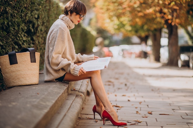 Foto gratuita mujer joven, sentado, en el estacionamiento, y, lectura