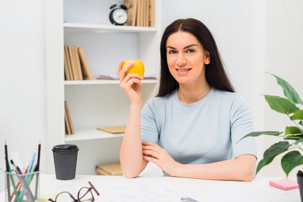 Mujer joven, sentado, con, manzana, en, oficina