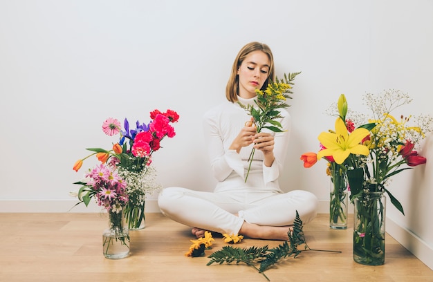 Mujer joven, sentado, con, plantas, en, piso