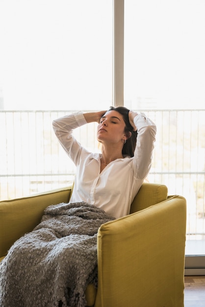 Foto gratuita mujer joven, sentado, en, sillón, relajante, en, balcón