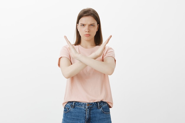 Mujer joven seria prohíbe la acción, diga que se detenga, prohíba y haga un gesto tabú, advirtiendo a la persona