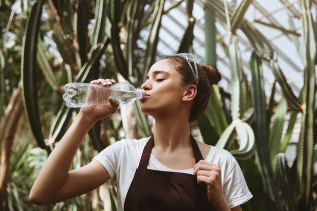 Mujer joven seria que se coloca en agua potable del invernadero.