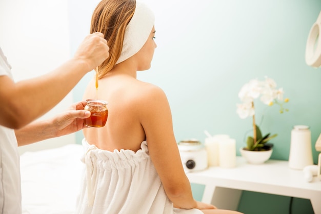 Foto gratuita mujer joven durante una sesión de depilación con miel en un spa de belleza