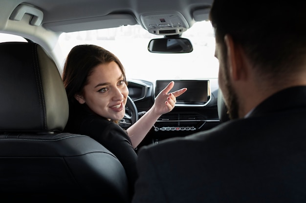 Foto gratuita mujer joven siendo un conductor uber para un cliente masculino