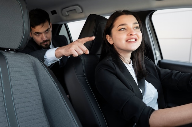 Mujer joven siendo un conductor uber para un cliente masculino