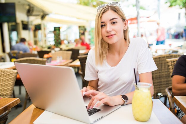 Mujer joven se sienta delante de la computadora portátil abierta