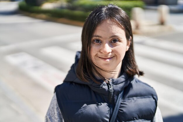 Mujer joven con síndrome de down sonriendo segura de pie en la calle