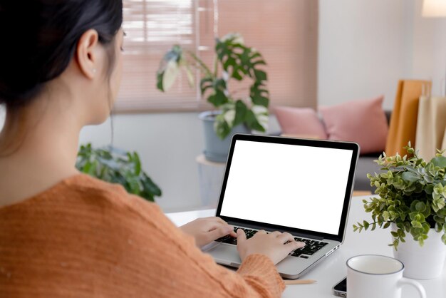 Mujer joven sobre el hombro usando una computadora portátil con pantalla en blanco