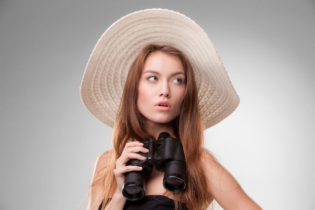 Mujer joven con sombrero con binoculares