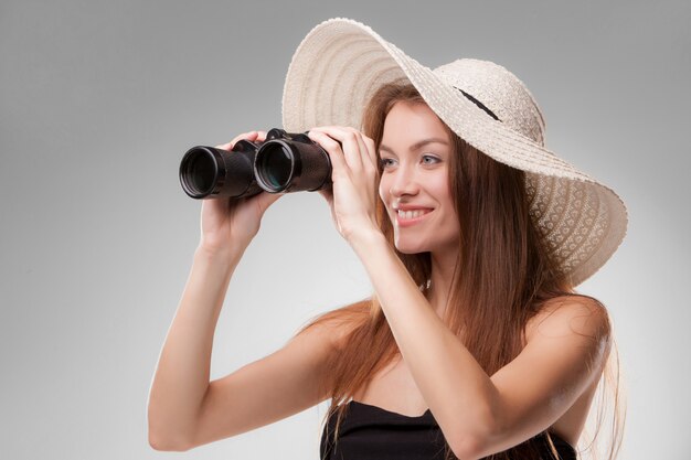 Mujer joven con sombrero con binoculares