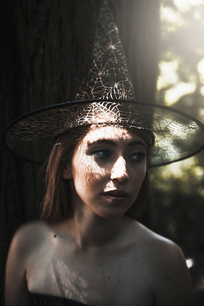 Mujer joven con sombrero de bruja en el parque