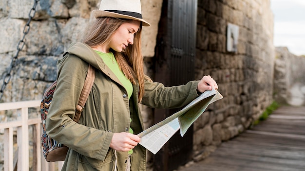 Mujer joven con sombrero comprobando el mapa