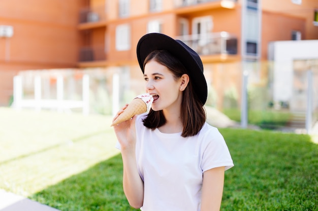 Mujer joven con sombrero disfrutar de un helado en la calle