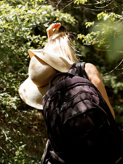 Mujer joven con sombrero explorando bosque