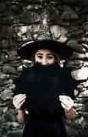 Foto gratuita mujer joven en sombrero de mago que cierra la boca con la decoración de halloween