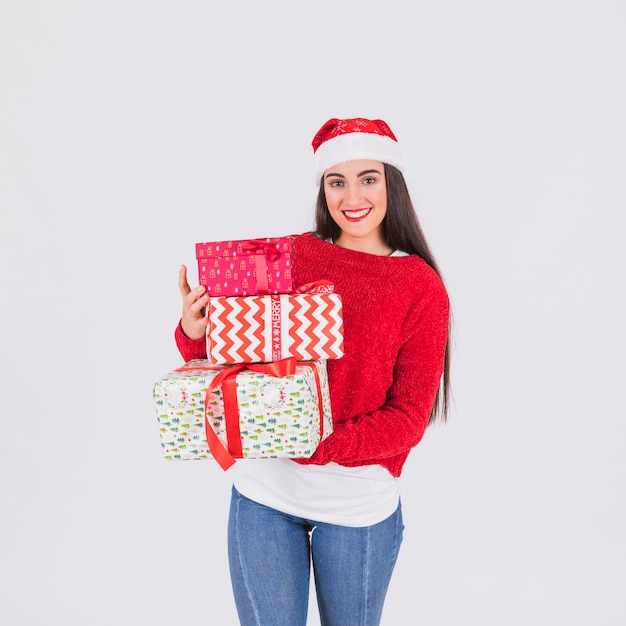 Mujer joven en sombrero de navidad y cajas presentes