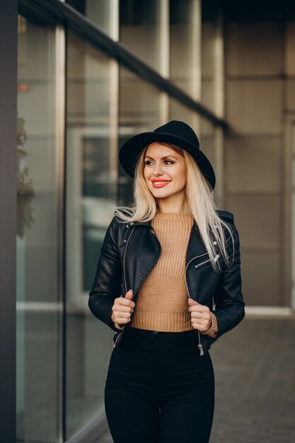 Mujer joven con sombrero negro caminando fuera de la calle