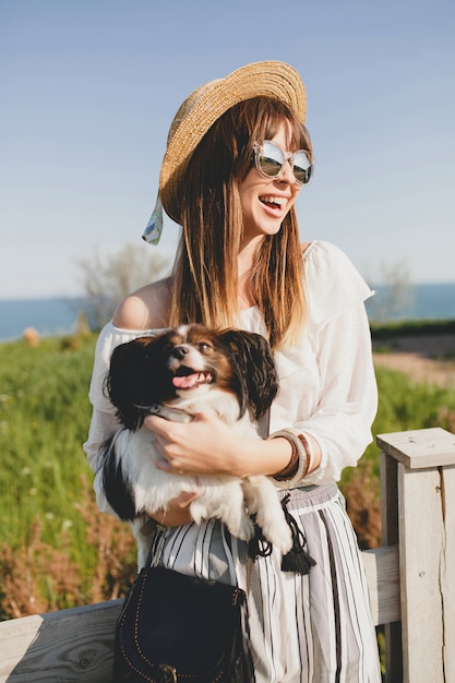 Mujer joven con sombrero de paja con su perro por la valla en el campo