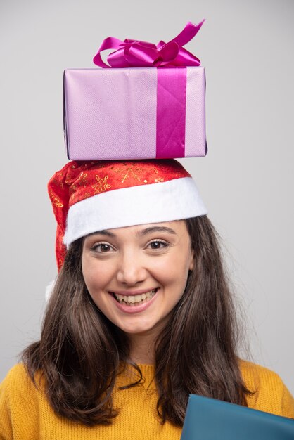 Mujer joven con sombrero de Santa con cajas de regalo encima.