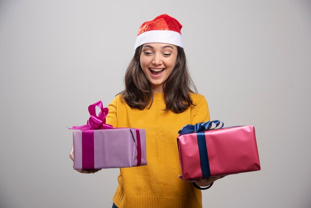 Mujer joven con sombrero de Santa mirando sus cajas.