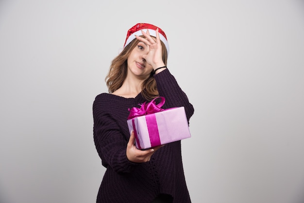 Foto gratuita mujer joven con sombrero de santa sosteniendo una caja de regalo presente.