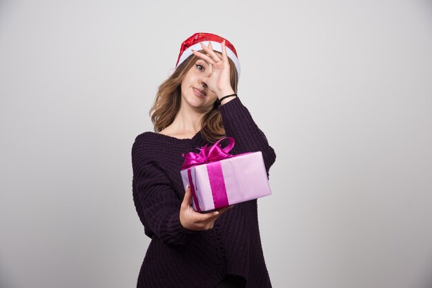 Mujer joven con sombrero de Santa sosteniendo una caja de regalo presente.