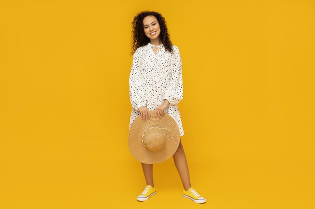 Mujer joven con sombrero sobre fondo amarillo