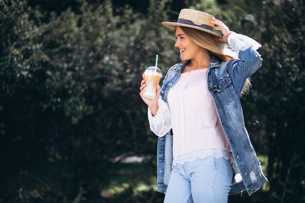 Mujer joven con sombrero tomando café para llevar