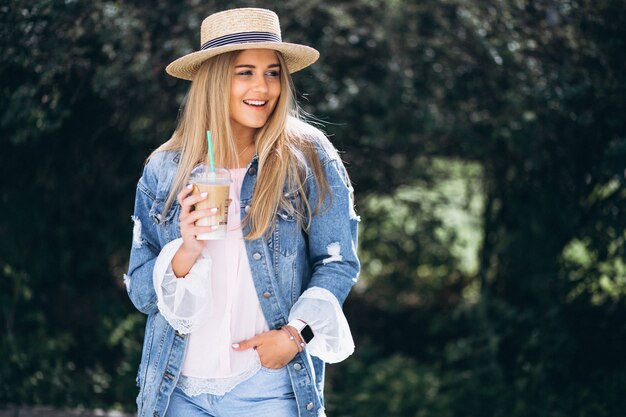 Mujer joven con sombrero tomando café para llevar