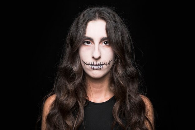 Mujer joven sombría con maquillaje de espantapájaros