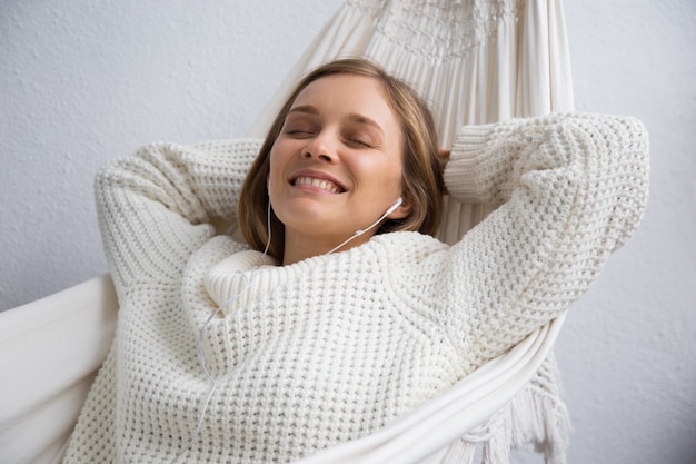 Mujer joven soñadora sonriente que se relaja en hamaca